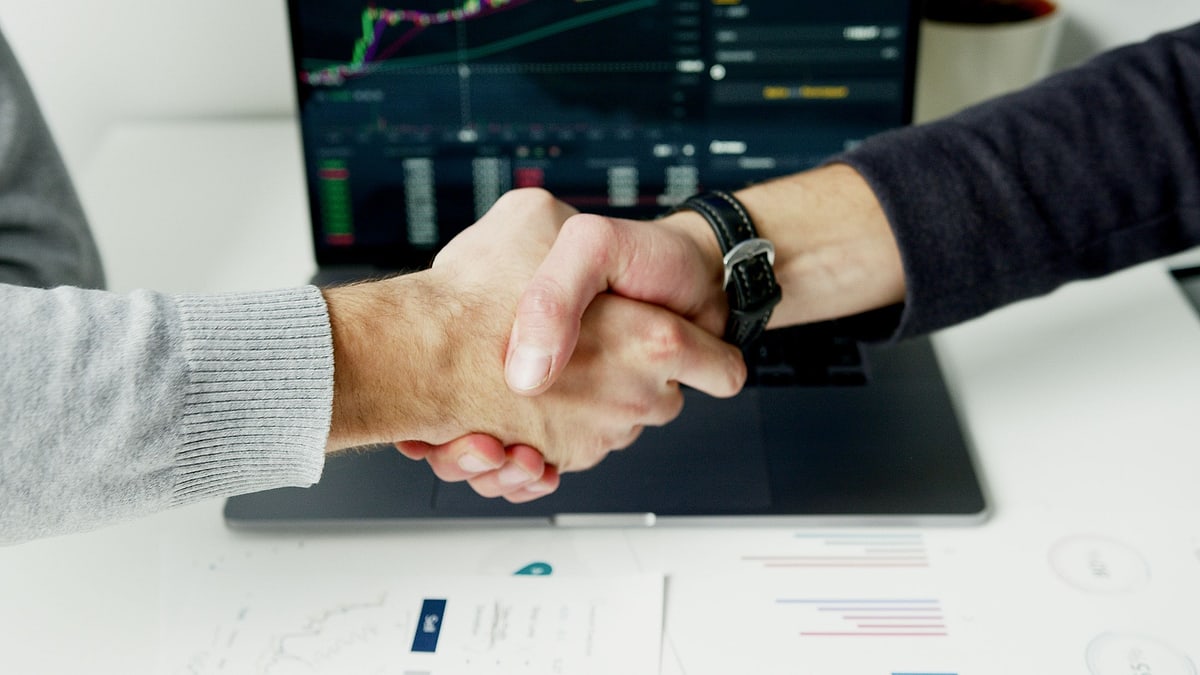 Finansal grafiklerin önünde anlaşmayı onaylayan el sıkışma